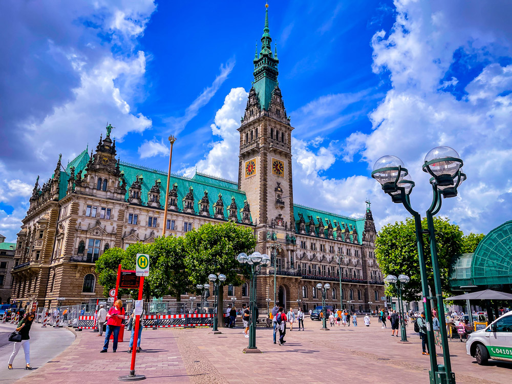 Image Hamburg's City Hall with blue skies, gothic style building with a clock tower and aged green roofing probably from aged copper